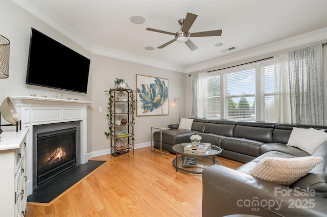 15807 Foreleigh Rd, Huntersville, NC 28078 - living room featuring a glass covered fireplace, crown molding, light wood-type flooring, a ceiling fan, and baseboards