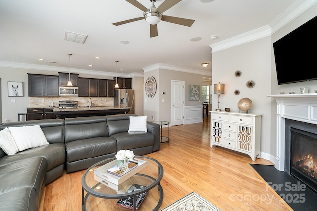 15807 Foreleigh Rd, Huntersville, NC 28078 - living area featuring a ceiling fan, a fireplace with flush hearth, ornamental molding, and light wood-type flooring