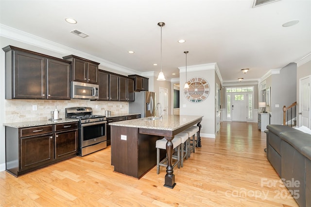 15807 Foreleigh Rd, Huntersville, NC 28078 - kitchen with appliances with stainless steel finishes, light wood-style floors, dark brown cabinetry, a kitchen breakfast bar, and ornamental molding