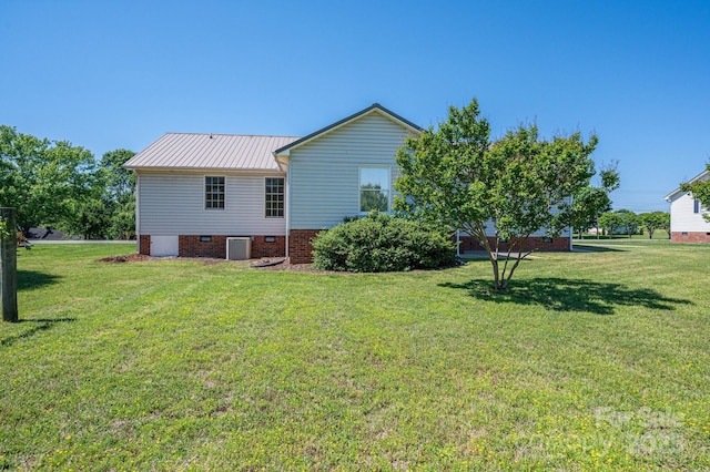 back of property featuring a lawn, central AC unit, metal roof, and crawl space