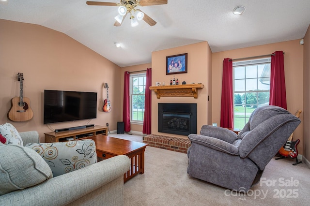 carpeted living room featuring a glass covered fireplace, baseboards, a ceiling fan, and lofted ceiling