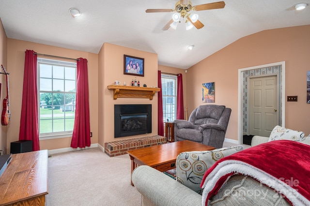 carpeted living area with lofted ceiling, a fireplace, baseboards, plenty of natural light, and a ceiling fan