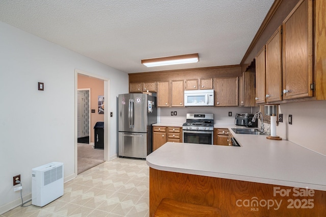 kitchen with a sink, light countertops, stainless steel appliances, and brown cabinets