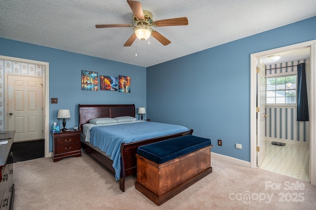 carpeted bedroom featuring baseboards, ceiling fan, ensuite bathroom, and a textured ceiling