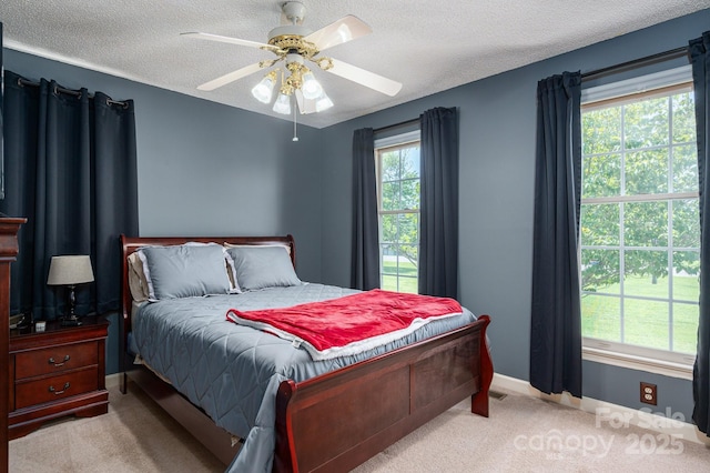 carpeted bedroom with a textured ceiling, ceiling fan, and baseboards
