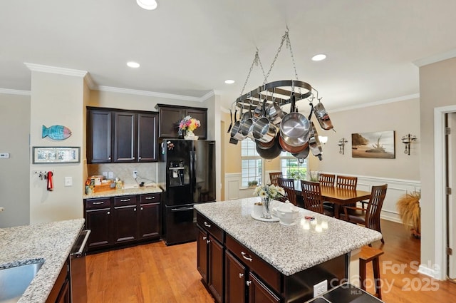 kitchen with light wood-type flooring, crown molding, and black refrigerator with ice dispenser