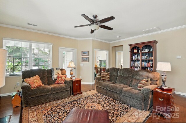 living room featuring visible vents, ornamental molding, wood finished floors, baseboards, and a ceiling fan