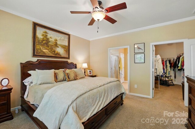 bedroom featuring crown molding, baseboards, light colored carpet, and a walk in closet