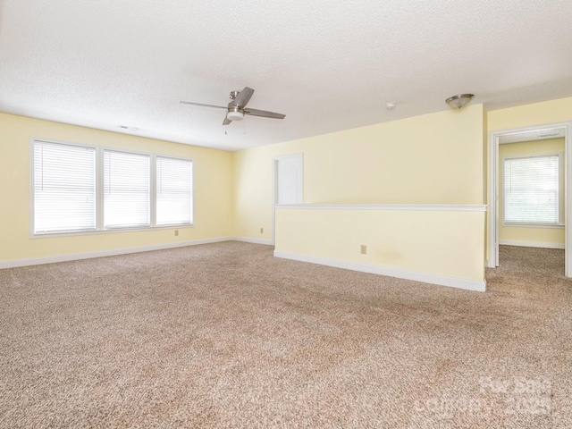 empty room featuring carpet flooring, a ceiling fan, a textured ceiling, and a wealth of natural light