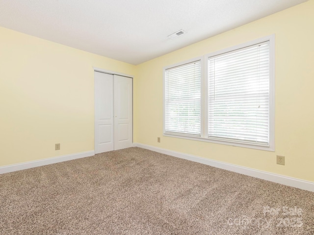 unfurnished bedroom with a closet, baseboards, carpet flooring, and visible vents