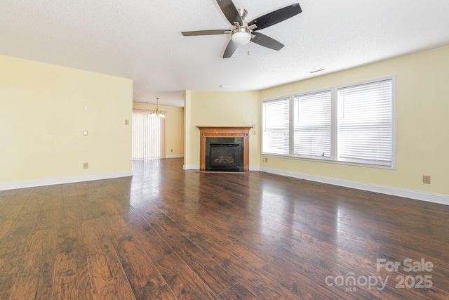 unfurnished living room featuring a fireplace with flush hearth, a healthy amount of sunlight, wood finished floors, and ceiling fan with notable chandelier
