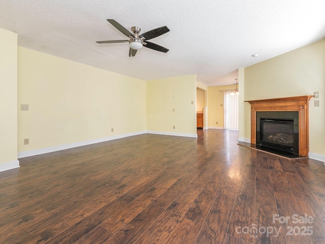 unfurnished living room with a textured ceiling, dark wood finished floors, a glass covered fireplace, and ceiling fan with notable chandelier