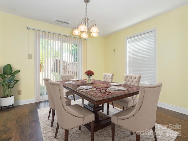 dining room with an inviting chandelier, baseboards, wood finished floors, and visible vents