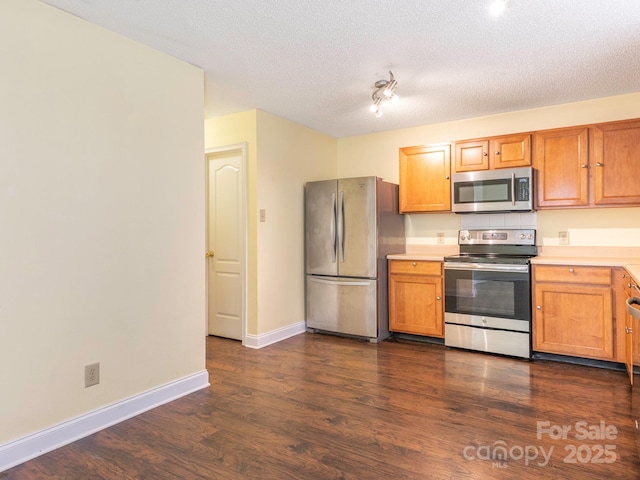 kitchen with baseboards, dark wood-style floors, light countertops, a textured ceiling, and appliances with stainless steel finishes