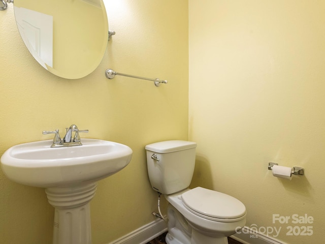 half bath with baseboards and toilet