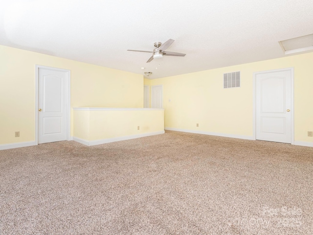 empty room with visible vents, baseboards, attic access, ceiling fan, and carpet flooring
