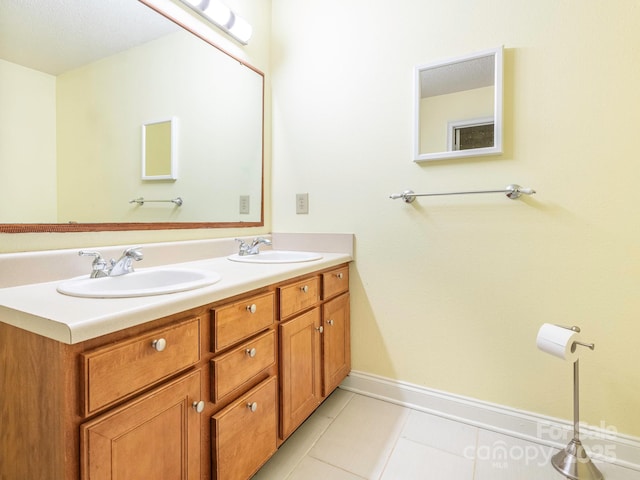 full bathroom with a sink, baseboards, tile patterned flooring, and double vanity