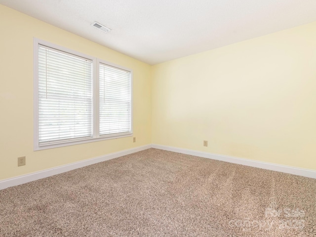 unfurnished room with baseboards, visible vents, and light carpet
