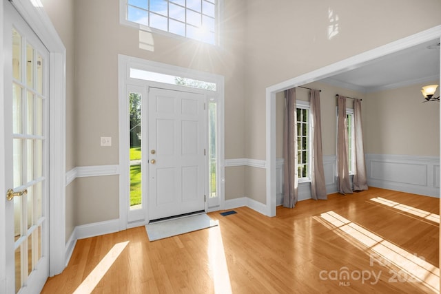 2608 Carmarthen Ct, Matthews, NC 28104 - foyer entrance featuring wood finished floors, a wainscoted wall, ornamental molding, and a towering ceiling