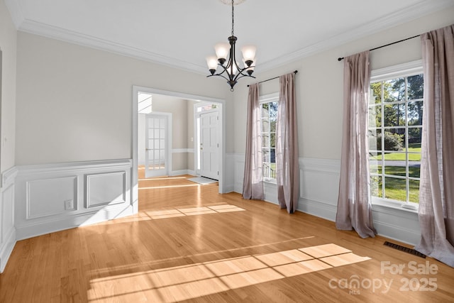 2608 Carmarthen Ct, Matthews, NC 28104 - unfurnished dining area featuring a chandelier, wood finished floors, plenty of natural light, ornamental molding, and a wainscoted wall