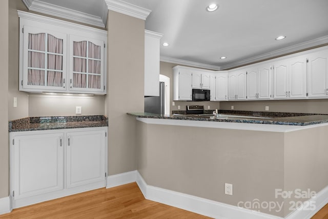 2608 Carmarthen Ct, Matthews, NC 28104 - kitchen featuring stainless steel appliances, white cabinetry, light wood-style flooring, a peninsula, and dark stone counters