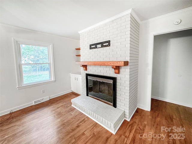 326 N Greenbriar Rd, Statesville, NC 28625 - unfurnished living room with visible vents, crown molding, a brick fireplace, and wood finished floors