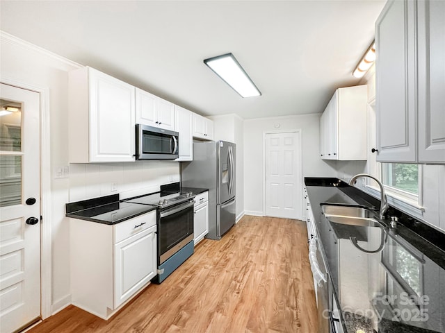 326 N Greenbriar Rd, Statesville, NC 28625 - kitchen featuring appliances with stainless steel finishes, dark countertops, a sink, light wood finished floors, and white cabinetry