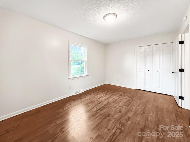 326 N Greenbriar Rd, Statesville, NC 28625 - unfurnished bedroom with a textured ceiling, baseboards, wood finished floors, visible vents, and a closet