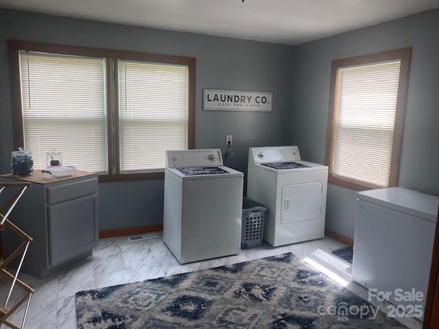 laundry area featuring washing machine and dryer, marble finish floor, and plenty of natural light