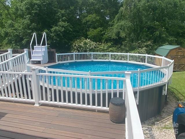 view of pool featuring a fenced in pool, a wooden deck, and a storage unit