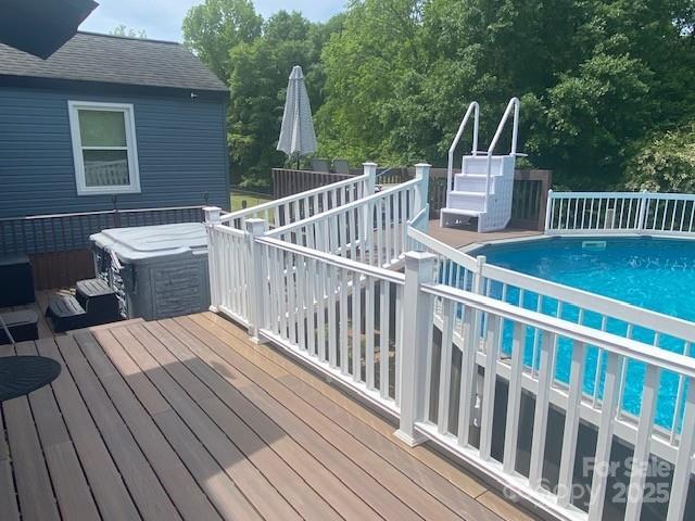 deck with a jacuzzi and an outdoor pool