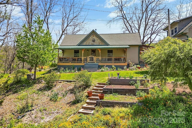 view of front of property featuring a shingled roof, a porch, and a front yard