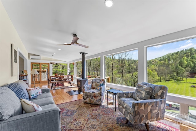 sunroom featuring a wall mounted AC, a wood stove, vaulted ceiling, wood finished floors, and recessed lighting