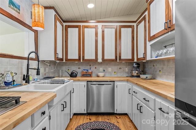 kitchen featuring butcher block countertops, light wood-type flooring, tasteful backsplash, a sink, and stainless steel appliances
