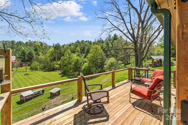 wooden terrace with a lawn and a view of trees