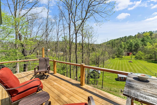 wooden deck with a yard and a view of trees