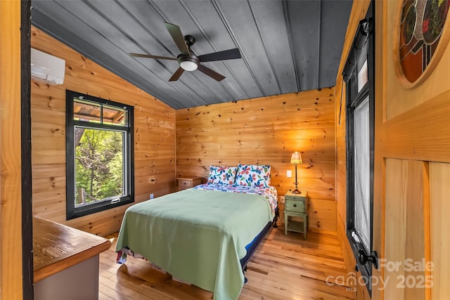 bedroom with wooden walls, ceiling fan, hardwood / wood-style floors, and lofted ceiling