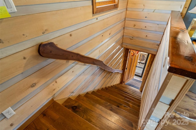 stairway with wood walls and hardwood / wood-style flooring