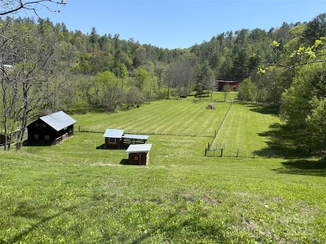 view of home's community featuring a lawn, a rural view, fence, and an outdoor structure