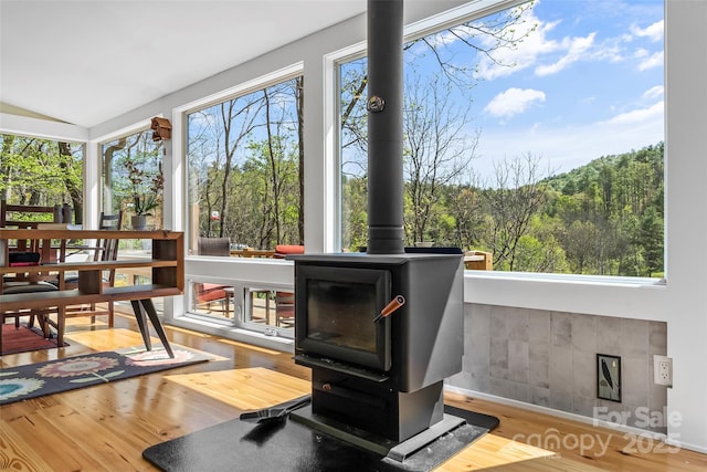 sunroom / solarium with a wood stove and a forest view