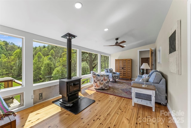 sunroom featuring a wood stove and a forest view