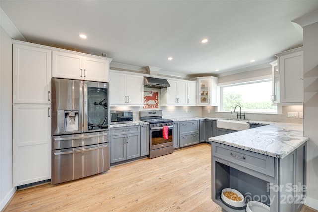 kitchen with ventilation hood, decorative backsplash, light stone countertops, gray cabinetry, and appliances with stainless steel finishes