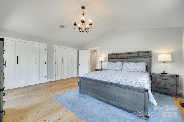 bedroom with two closets, a chandelier, wood finished floors, and lofted ceiling