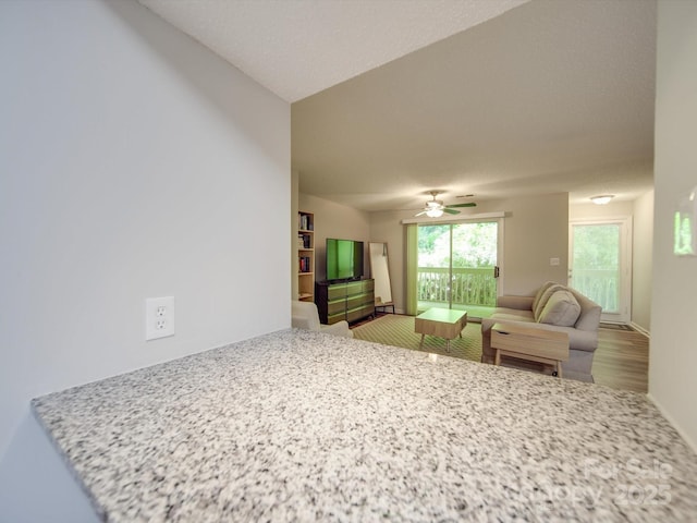 living room with baseboards and ceiling fan