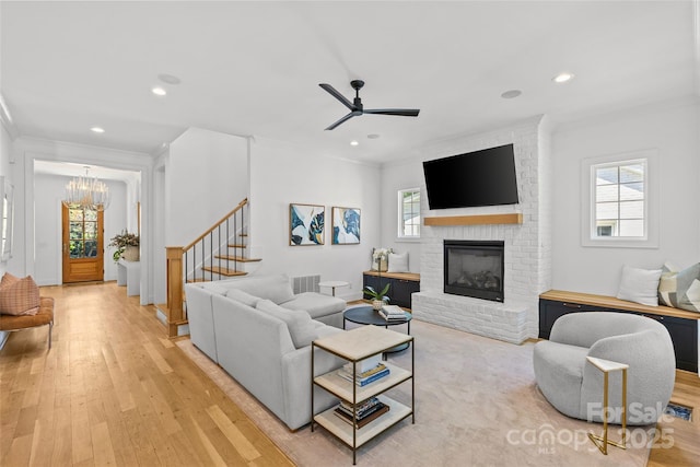 2509 Bay St, Charlotte, NC 28205 - living area featuring light wood-style flooring, ornamental molding, a brick fireplace, a chandelier, and stairs