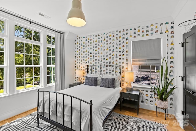 2509 Bay St, Charlotte, NC 28205 - bedroom with multiple windows, baseboards, an accent wall, wallpapered walls, and wood finished floors
