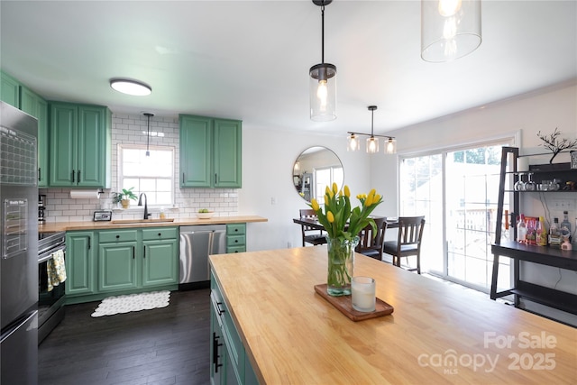 kitchen featuring stainless steel appliances, wooden counters, a sink, and green cabinets
