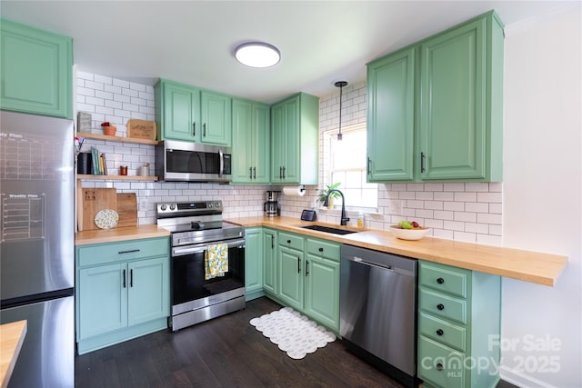 kitchen featuring a sink, appliances with stainless steel finishes, decorative backsplash, and butcher block countertops