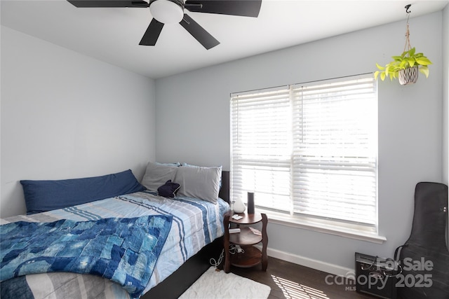 bedroom with baseboards, ceiling fan, wood finished floors, and multiple windows