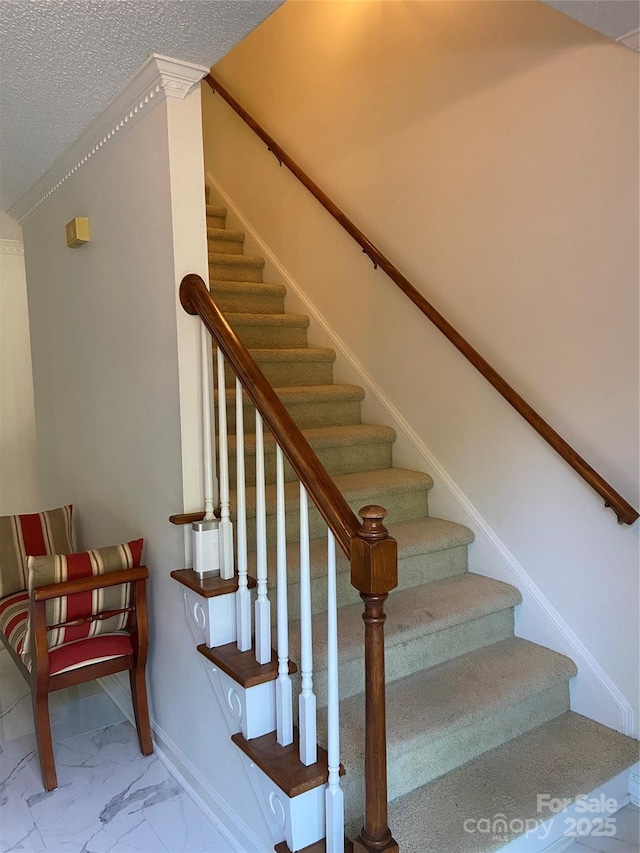 stairs with baseboards, a textured ceiling, marble finish floor, and ornamental molding